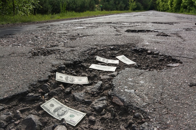 Dollar bills in the potholes on road