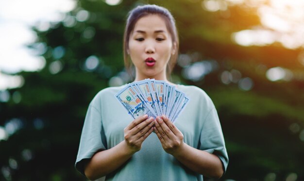 Dollar in the hands of an Asian woman Savings Investments Salary Income Cash Flow Happiness and Financial Success and Investments