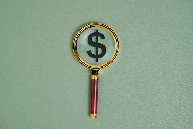 Dollar symbol under a magnifying glass on a green background