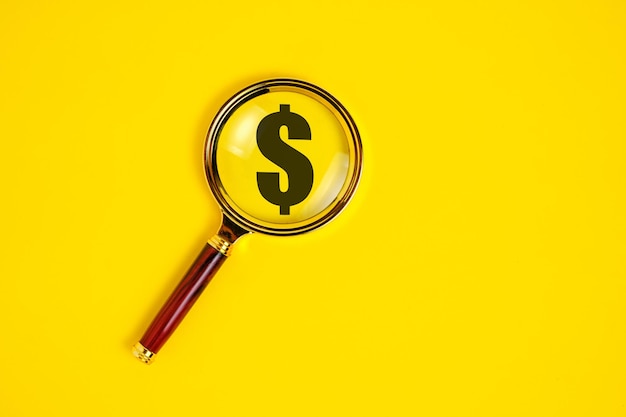 Dollar symbol under a magnifying glass on yellow background