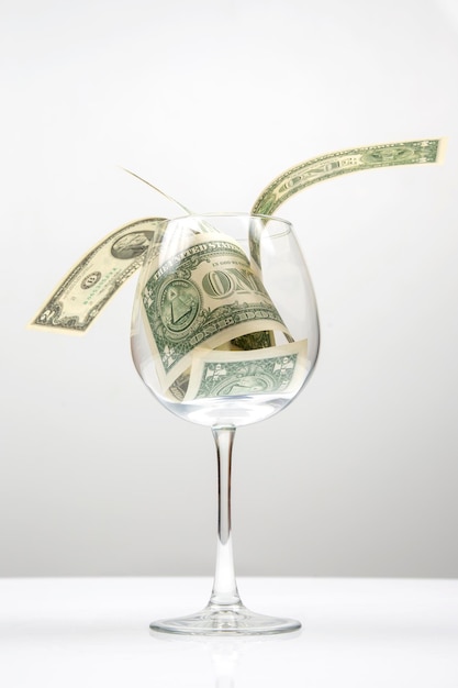 dollarbankbiljetten geld ligt in een leeg wijnglas. bedrijf in de wijnindustrie. alcohol marketing