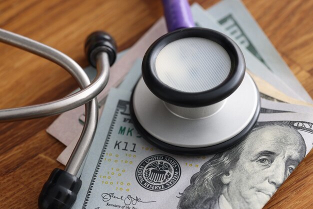 Dollarbiljetten op tafel met een stethoscoop erop steekpenningen in het concept van medische voorzieningen