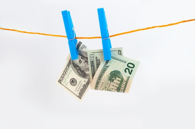 Dollars banknotes attached with clothespins to a rope on white isolated background