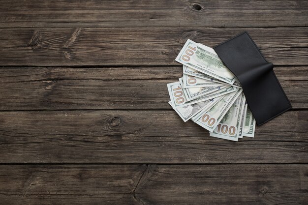 Dollars in  black wallet on old wooden background