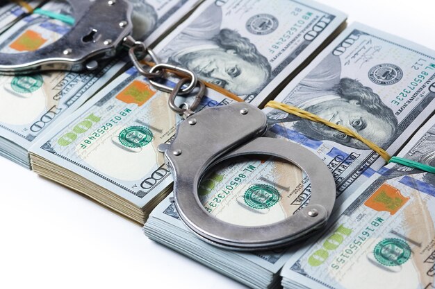 A dollars in bundles on white background with handcuffs crime fraud concept business pandemic