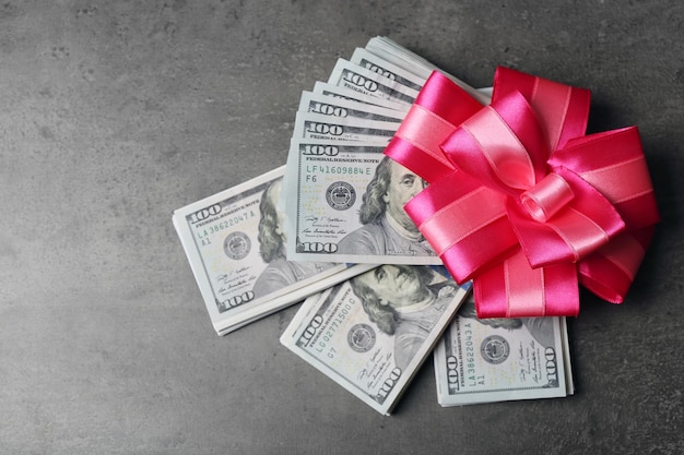Photo dollars and colorful bow on grey background