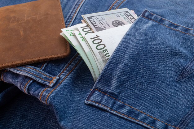 Dollars and euro sticking out of jeans pocket