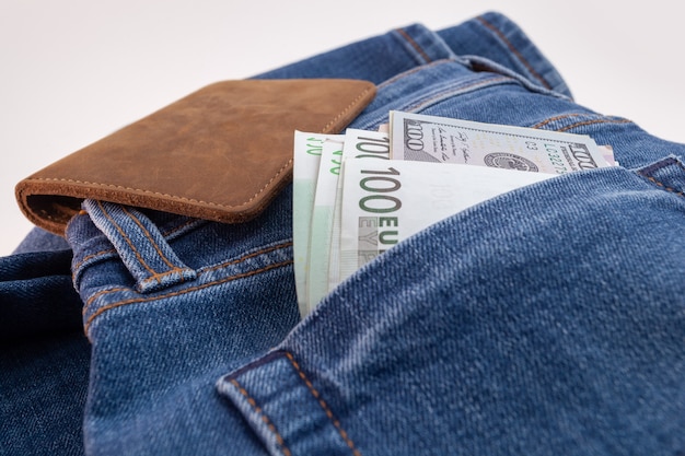 Dollars and euro sticking out of jeans pocket