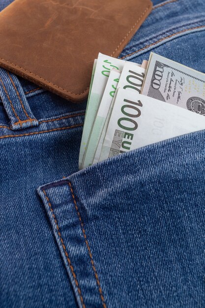 Dollars and euro sticking out of jeans pocket