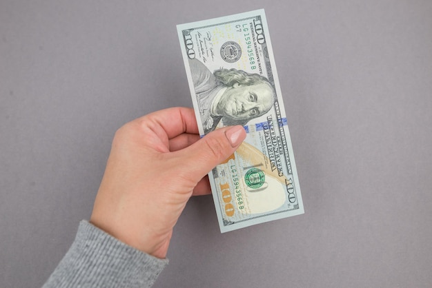 Dollars in a female hand on a gray background