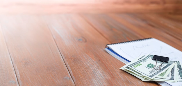 Photo dollars lie on top of a notebook on a wooden table