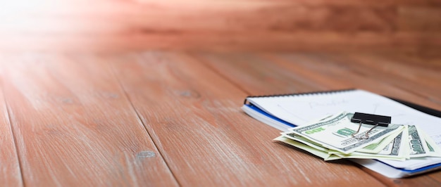 Dollars liggen bovenop een notitieboekje op een houten tafel