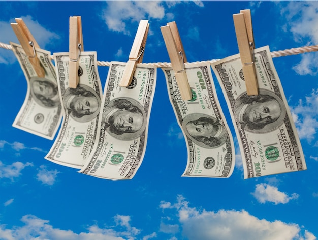 Dollars on the line with clothes pins on sky background