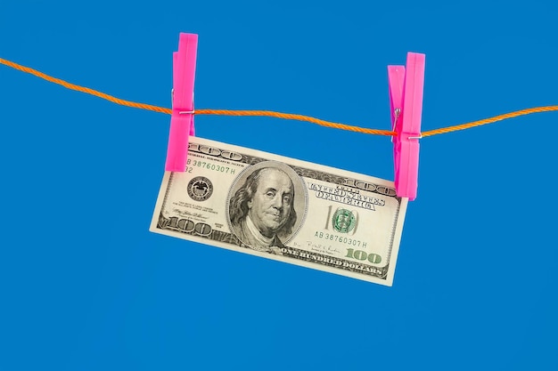 Dollars money on rope clothespin on blue background