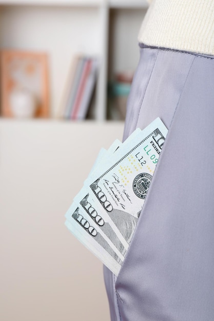 Dollars in pocket of gray pants on unfocused background closeup