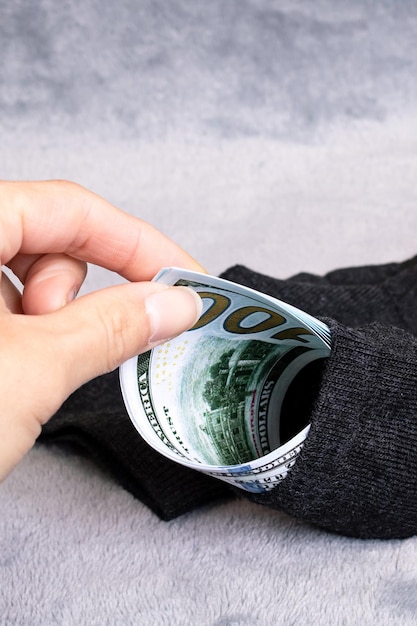 Dollars in sock and hand on gray background