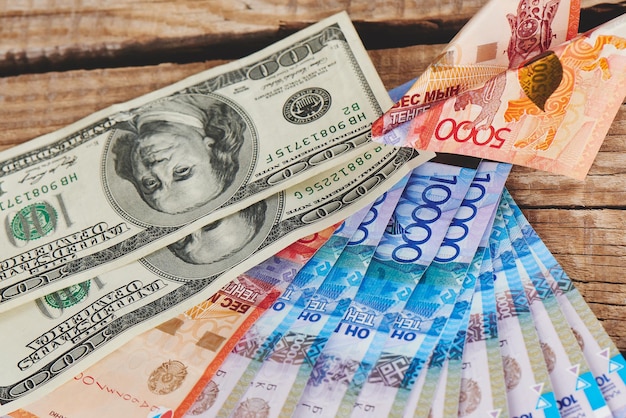 木製の背景にドルとテンゲ。カザフスタンの通貨。ビジネスとお金。