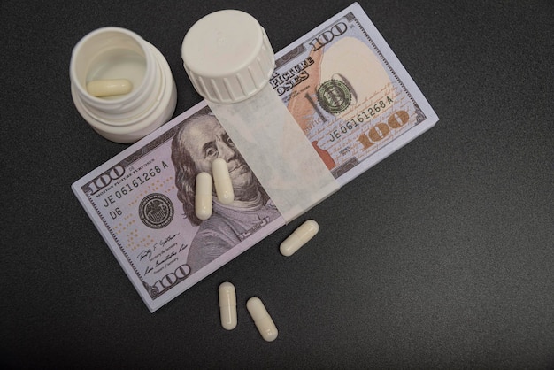 Dollars and white pills on a black background from up close