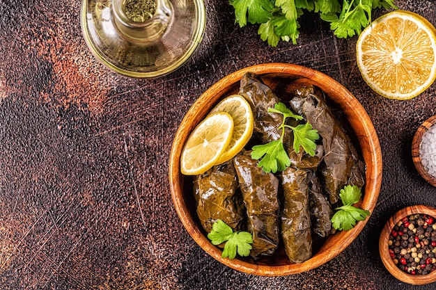 Dolma, gevulde druivenbladeren met rijst en vlees op donkere achtergrond, bovenaanzicht.