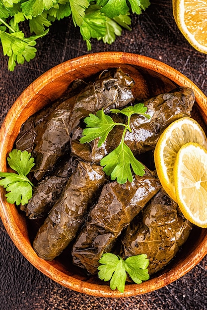 Dolma, gevulde druivenbladeren met rijst en vlees op donkere achtergrond, bovenaanzicht.