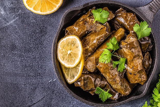 Dolma, stuffed grape leaves with rice and meat on dark background, top view.