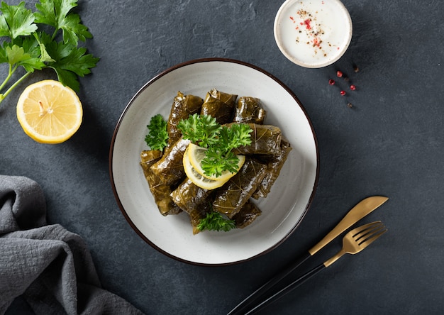 Dolma - stuffed grape leaves with rice and meat on a dark background, view from above. Traditional Greek. Caucasian and Turkish cuisine