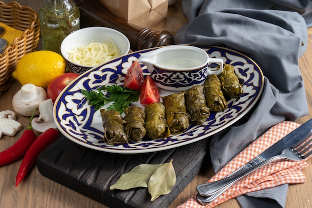 Dolma with vegetables and dill sauce on a plate with a traditional Uzbek 