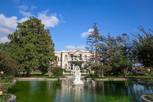 Dolmabahce Palace gardens with a lot of greenery, fountain and pond with water in Istanbul, Turkey