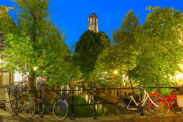 Torre del duomo e ponte con biciclette sul canale oudegracht di notte illuminazioni colorate