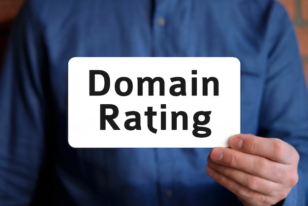 domain rating text on a white sign in the hand of a man in a blue shirt
