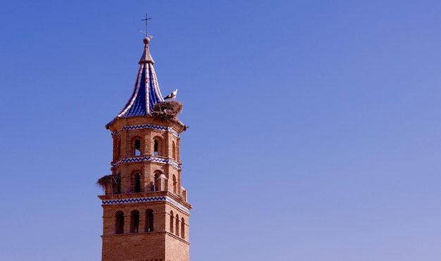 Dome of the catholic church made of red brick and decorated with blue and white ceramic tiles Stork nests on top Tauste Zaragoza province Aragon Spain