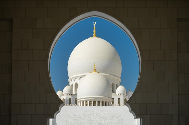 domes of sheikh zayed mosque seen through arch