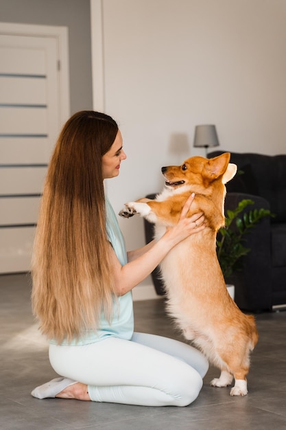 Cane corgi domestico con proprietario di una ragazza giovane donna seduta sul pavimento e abbraccio welsh corgi pembroke lifestyle con cane giocoso domestico