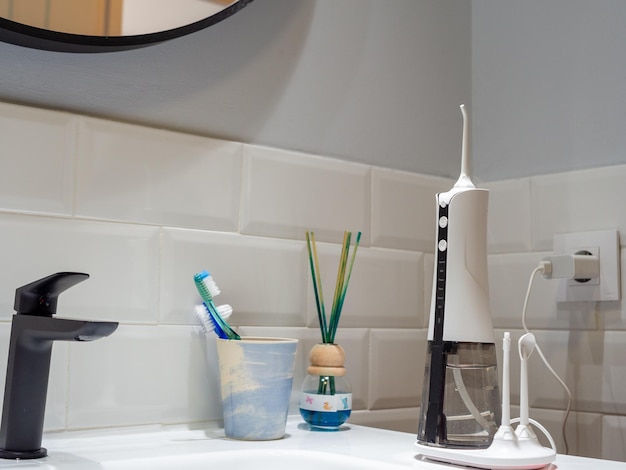 Photo domestic dental water flosser on the bathroom wash basin