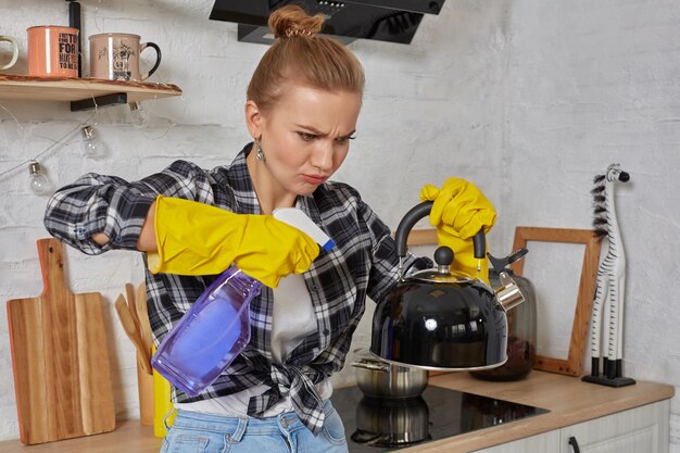 Domestic service and housekeeping concept happy blonde lady cleaning kitchen kettle