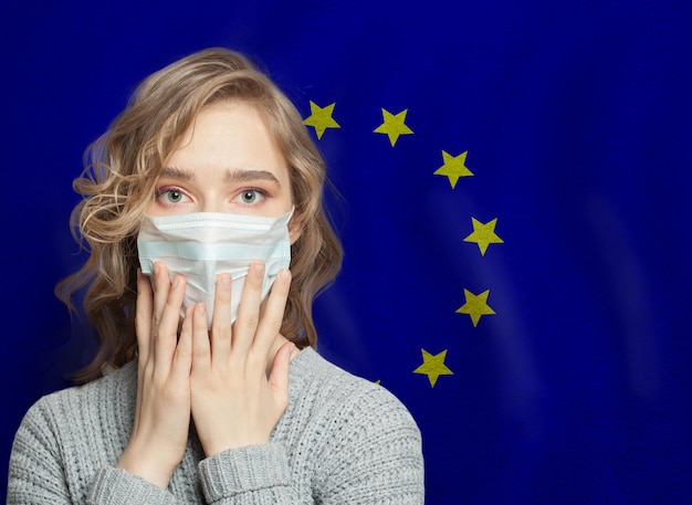 Фото Насилие в семье и эпидемия гриппа в европейском союзе шокирующая женщина в медицинской маске на фоне флага ес