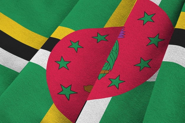 Dominica-vlag met grote vouwen die van dichtbij onder het studiolicht binnen zwaaien De officiële symbolen en kleuren in banner