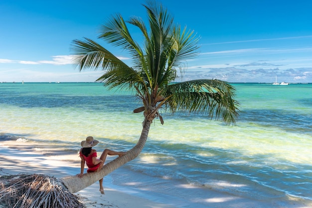 プンタ カナのドミニカ共和国、ターコイズ ブルーの水とヤシの木と海の上の帽子の少女