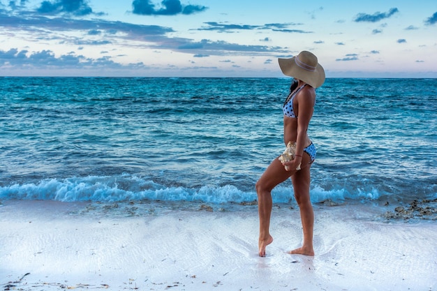 Dominican Republic of Punta Cana a girl in a hat on the ocean with turquoise water and palm trees