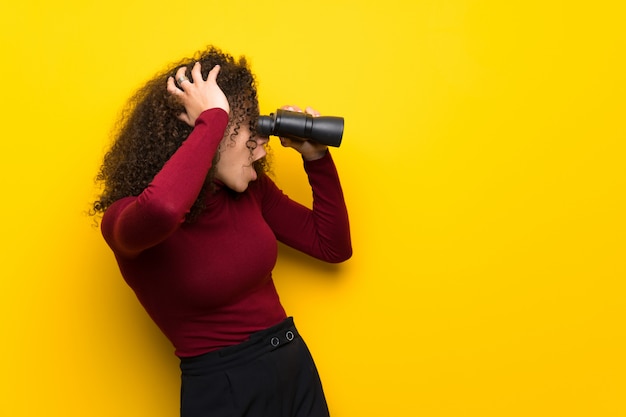 Dominican woman with turtleneck sweater and looking in the distance with binoculars