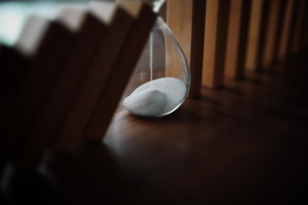 Domino effect concept with wooden tiles blocked by hourglass with background