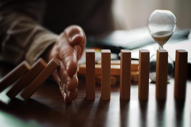 Domino effect concept with wooden tiles blocked by hourglass with background