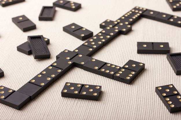 Domino pieces in black on a light table