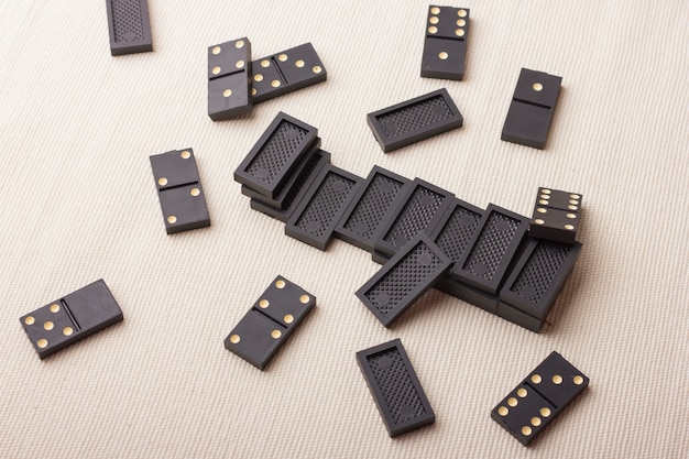 Domino pieces in black on a light table