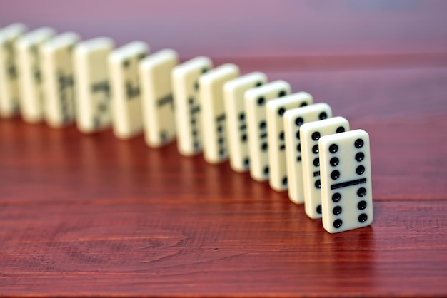 Dominoes are lined up on a wooden table