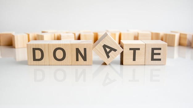 Donate text on a wooden blocks, gray background.