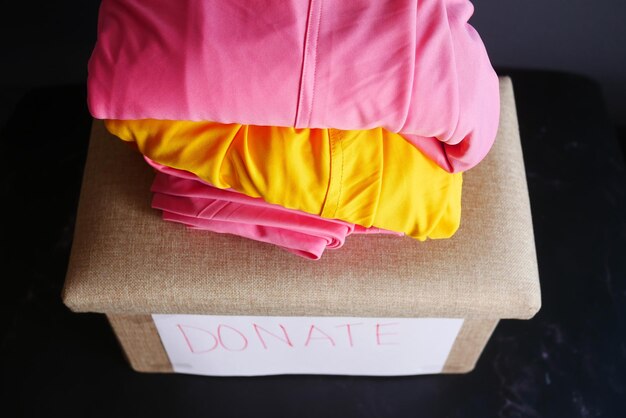 Foto donatiedoos met donatiekleren op een houten tafel