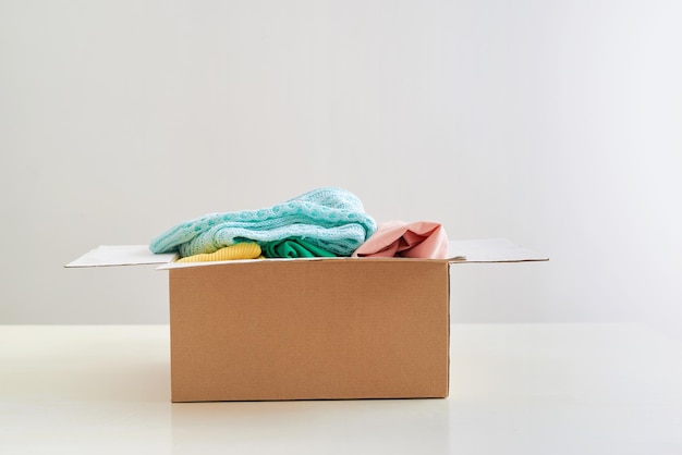 Foto donatiedoos met kleren op tafel tegen witte achtergrond