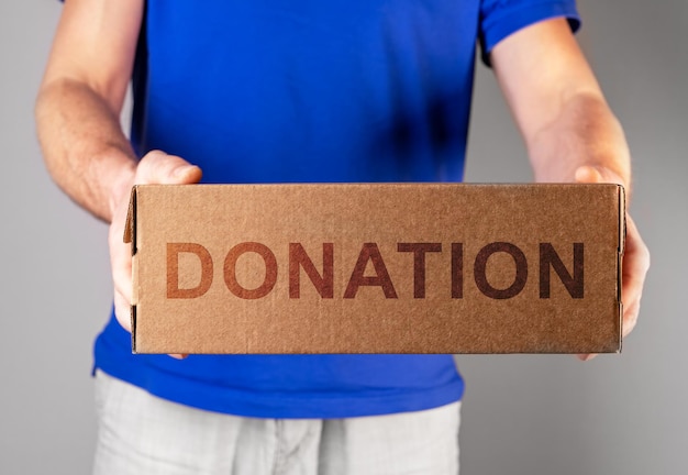 Donation box in hand of male volunteer donating smth Help charitable aid in cardboard