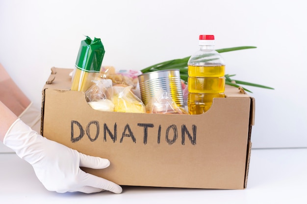 donation box. in hands in rubber gloves is a cardboard box.